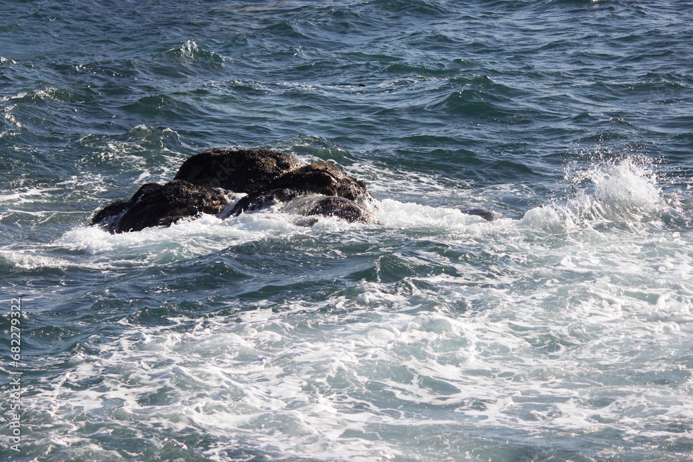 Obraz premium Background close-up photo of sea waves crashing on the beach, a rock in the background makes up the landscape.