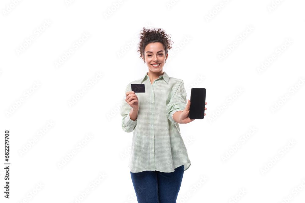 portrait of a charming sympathetic caucasian woman with black curly hair in a light shirt holding a plastic card and a smartphone portrait of a charming sympathetic caucasian woman with black curly hair in a light shirt holding a plastic card and a smartphone