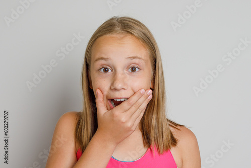 Happy excited young girl looking at camera against gray studio wall background