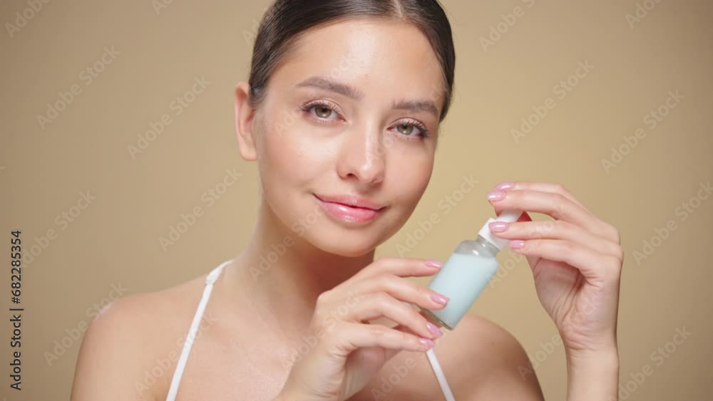 Beautiful young woman holding a cosmetic jar of oil serum or hyaluronic acid in her hand. Perfect facial skin. Cosmetic skin care Beautiful young woman holding a cosmetic jar of oil serum or hyaluronic acid in her hand. Perfect facial skin. Cosmetic skin care