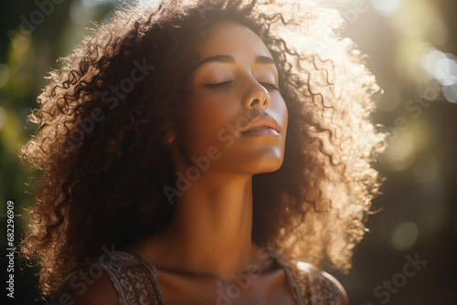 Portrait of a beautiful mixed race woman with curly brown hair in the sunlight in the field