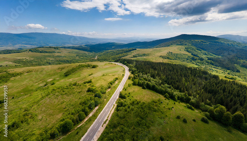 aerial view of countryside road passing through the green forest and mountain aerial view over mountain road going through forest landscape