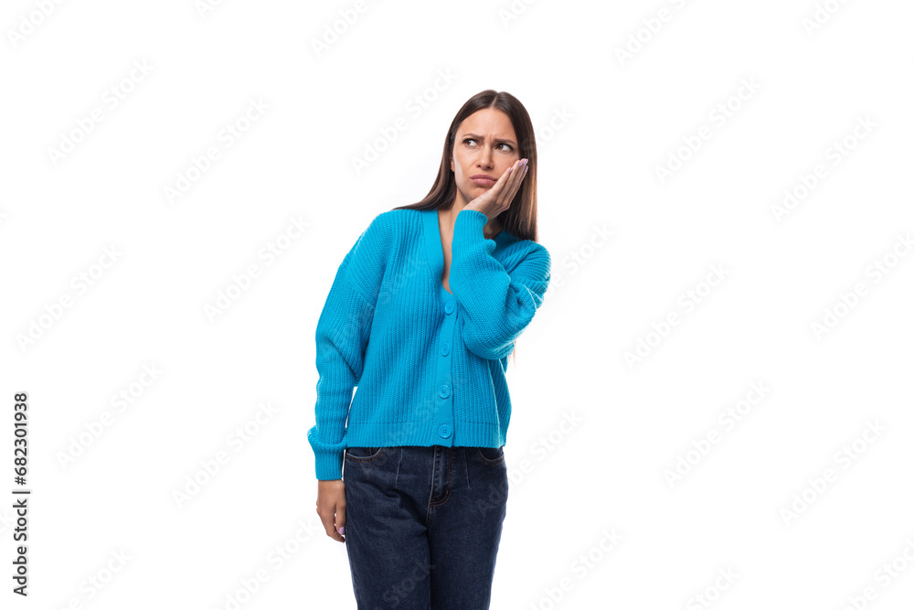 young stylish brunette lady dressed in a blue V-neck sweater is sad on a white background with copy space young stylish brunette lady dressed in a blue V-neck sweater is sad on a white background with copy space