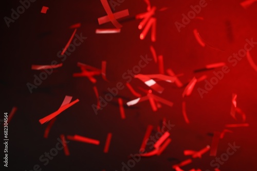 Shiny confetti falling down on dark red background