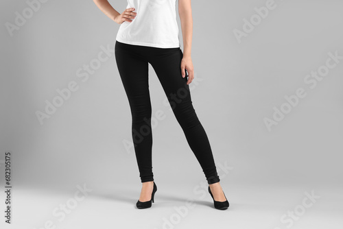 Woman wearing stylish black jeans and high heels shoes on light gray background, closeup