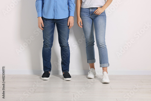 People in stylish jeans near white wall indoors, closeup