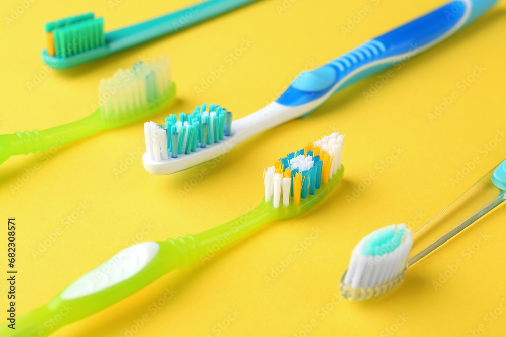 Many different toothbrushes on yellow background, closeup Many different toothbrushes on yellow background, closeup