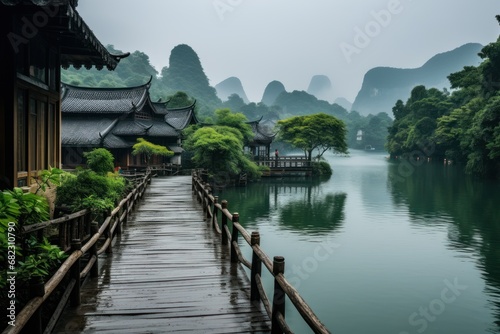  a wooden bridge over a body of water next to a lush green forest filled with trees and mountains on a foggy, overcast, overcast, overcast day.