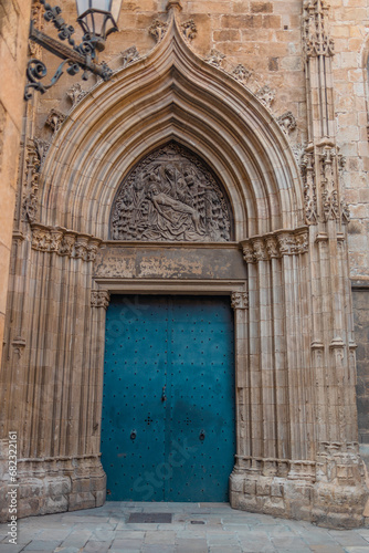 View of the old and beautiful art iron blue color door with doorknocker, classic architectural detail, stone semicircular arch with ornaments in the facade. Barcelona, Spain. 