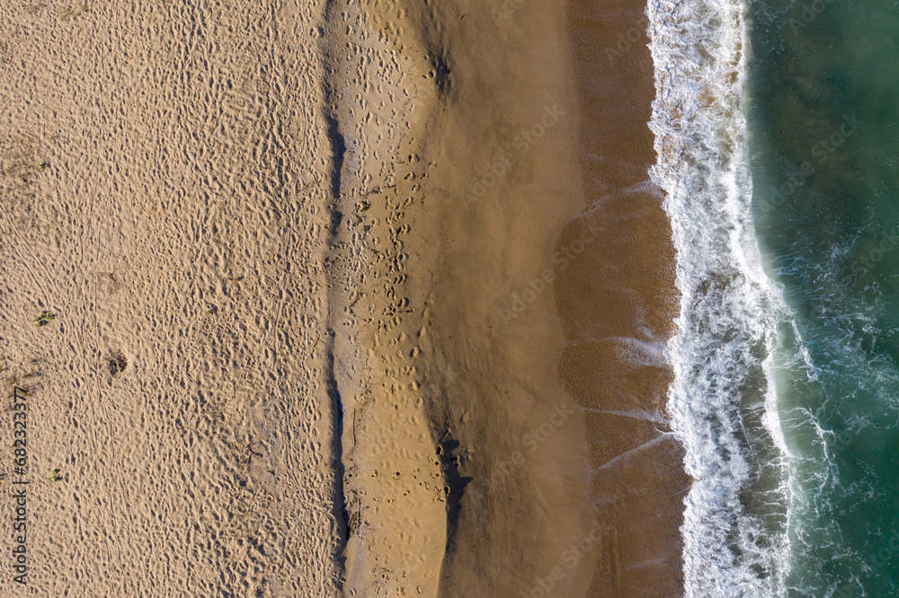 Aerial view of a remote sandy beach and sea waves