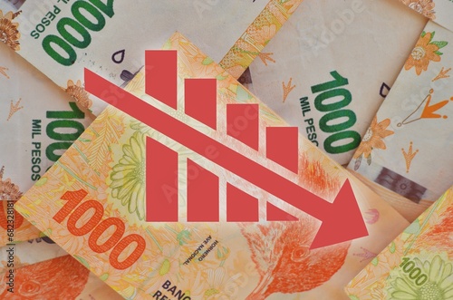 graph with downward arrows with Argentine currency bills in the background showing currency devaluation
