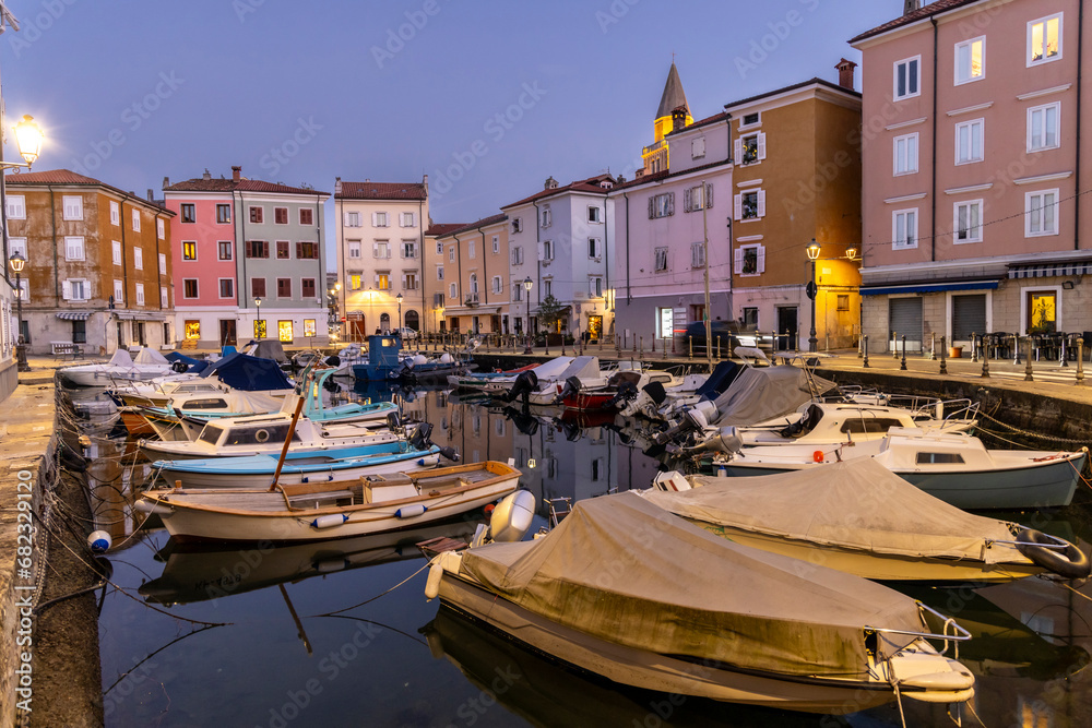 Evening atmosphere in the old harbour of Muggia, a coastal town near Trieste in northern Italy with moored small motor boats.