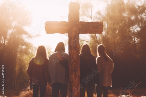 Kids, children holding hands and praying around wooden christian cross. Church worship, believe, camp concept photo