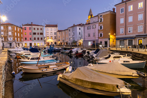 Obraz na płótnie Evening atmosphere in the old harbour of Muggia, a coastal town near Trieste in northern Italy with moored small motor boats. w salonie