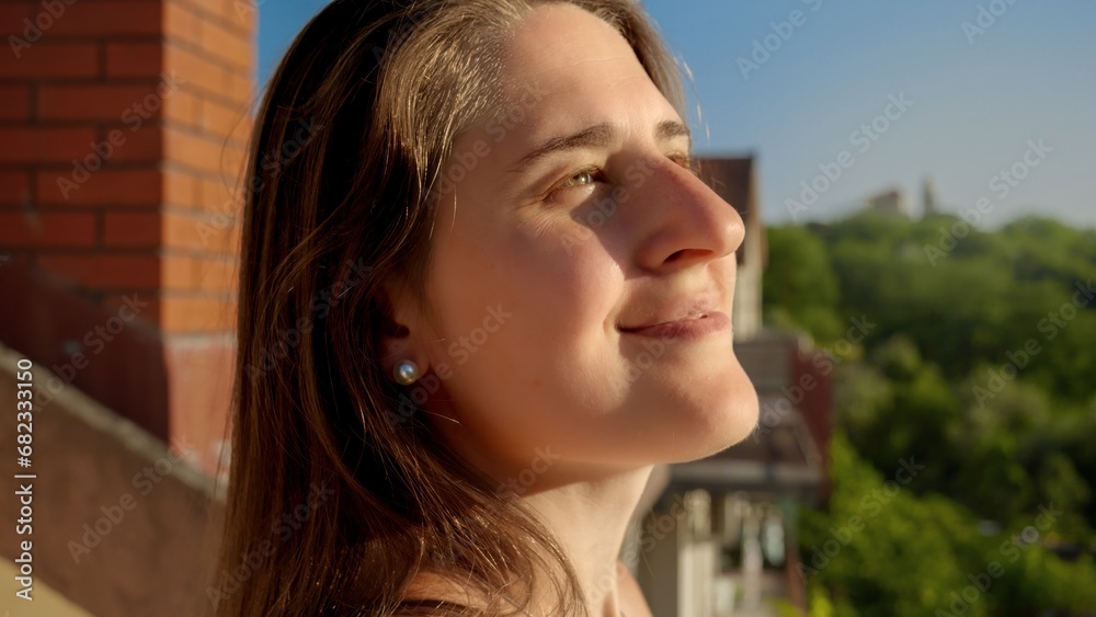 Portrait of smiling brunette woman looking on the setting sun from the balcony of villa Portrait of smiling brunette woman looking on the setting sun from the balcony of villa