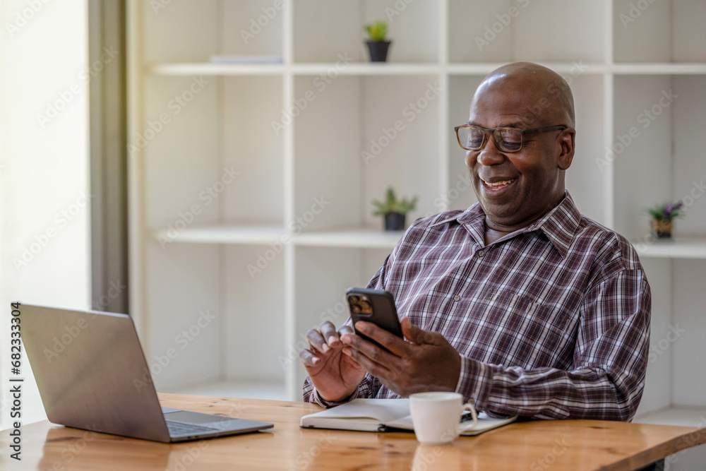 Senior black man talking on the phone and using at the laptop, video call recommend and consult. Senior black man talking on the phone and using at the laptop, video call recommend and consult.