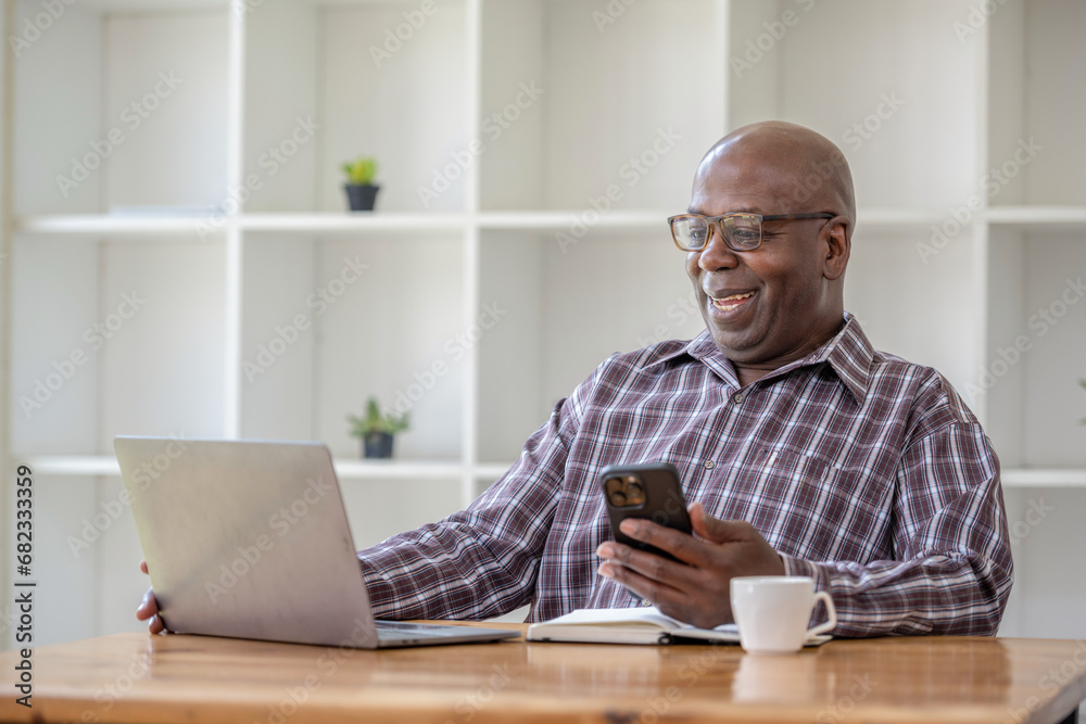 Senior black man talking on the phone and using at the laptop, video call recommend and consult. Senior black man talking on the phone and using at the laptop, video call recommend and consult.