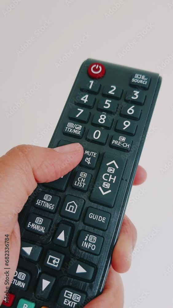 A hand is operating a television remote control. Change channels up and down, turn the volume up and down, and turn the power on and off. A hand is operating a television remote control. Change channels up and down, turn the volume up and down, and turn the power on and off.