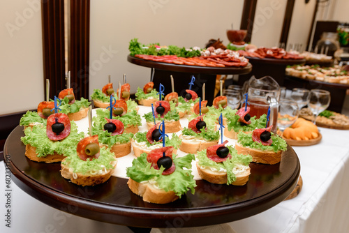 Canapes with olives, tomatoes and lettuce are served as an appetizer on the buffet table photo