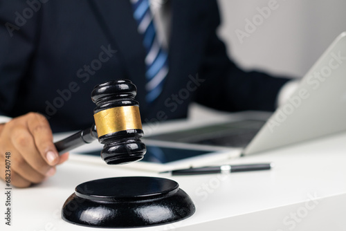 Justice, Law, Attorney and Court judge concept. Man judge hand holding gavel to bang on sounding block in the court room. Professional lawyer considering with contract papers in courtroom.