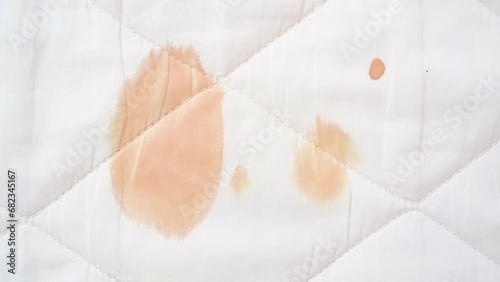 Red blood stains from a woman's menstrual period stain the white mattress cover photo
