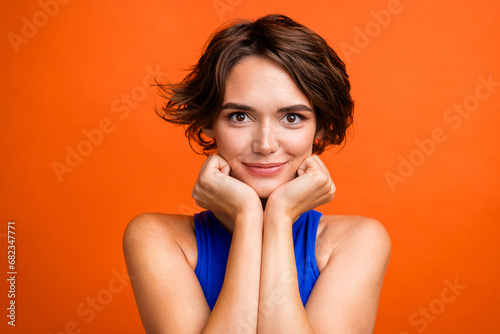 Photo of stunning positive peaceful lady hands touch cheeks isolated on vivid orange color background