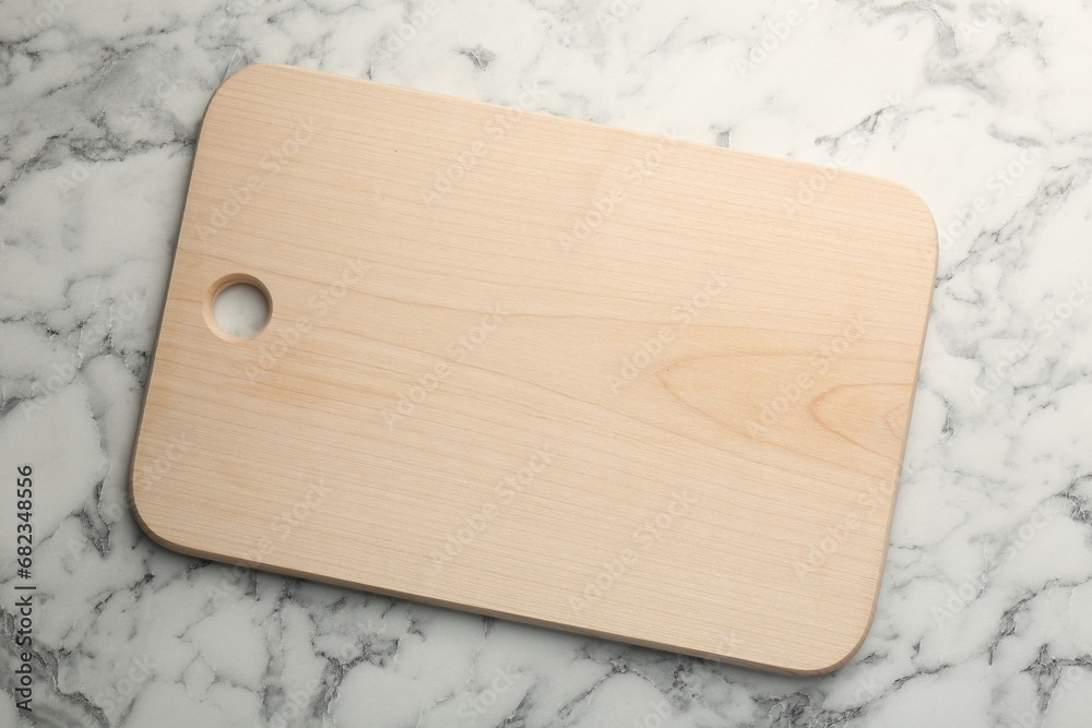 Wooden cutting board on white marble table, top view. Space for text