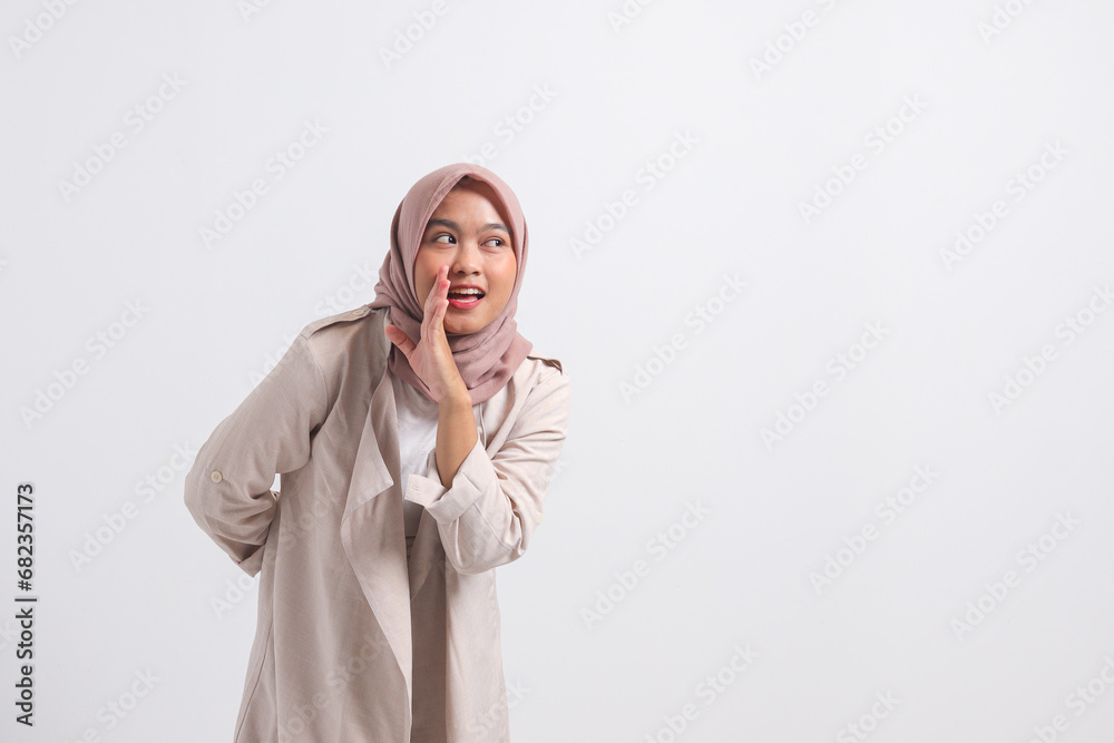 Portrait of excited Asian hijab woman in casual suit screaming announcement and whispering gossip. Businesswoman concept. Isolated image on white background Portrait of excited Asian hijab woman in casual suit screaming announcement and whispering gossip. Businesswoman concept. Isolated image on white background