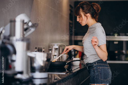 Young woman preparing breakfast in kitchen in the morning