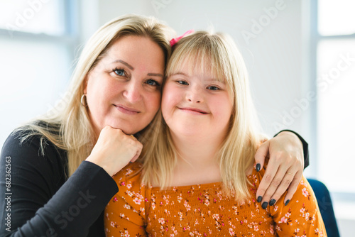 Mother and sweet down syndrome daughter girl at home sofa photo