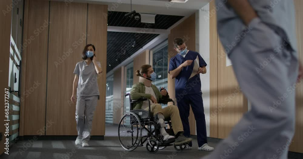 Side-view portrait of successful kind male doctor wearing uniform showing Caucasian man in wheelchair x-ray and consulting regarding injury. Professional physiotherapist and patient. Side-view portrait of successful kind male doctor wearing uniform showing Caucasian man in wheelchair x-ray and consulting regarding injury. Professional physiotherapist and patient.
