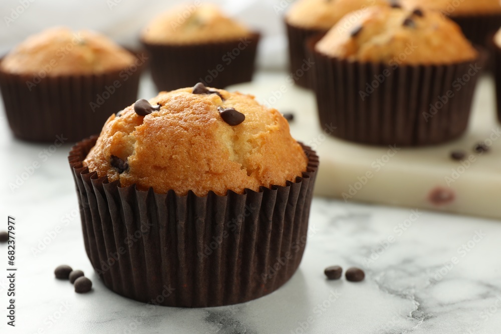 Delicious sweet muffin with chocolate chips on white marble table, closeup. Space for text Delicious sweet muffin with chocolate chips on white marble table, closeup. Space for text