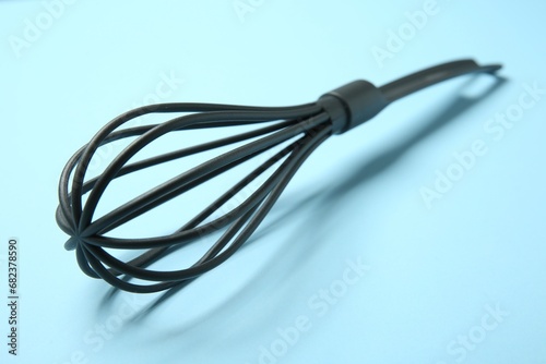 One whisk on light blue background, closeup