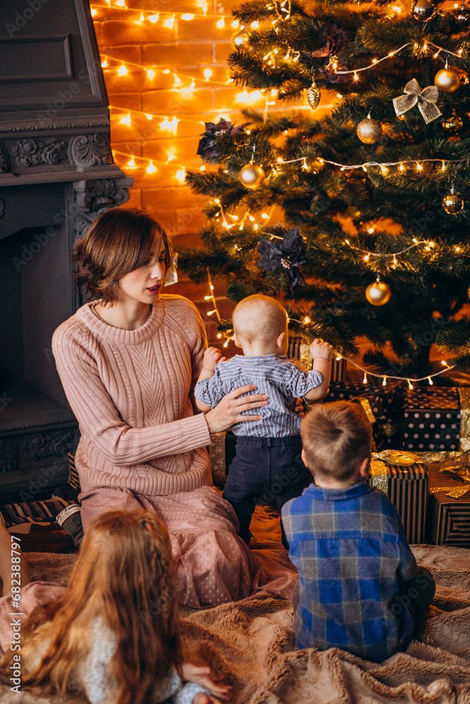 Mother with children sitting by Christmas tree