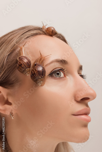 Beautiful woman with snails on her face.Cosmetology procedures,skin rejuvenation