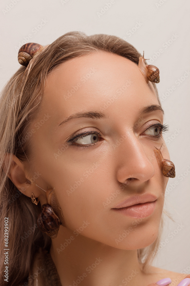 Naklejka premium Beautiful woman with snails on her face.Cosmetology procedures,skin rejuvenation