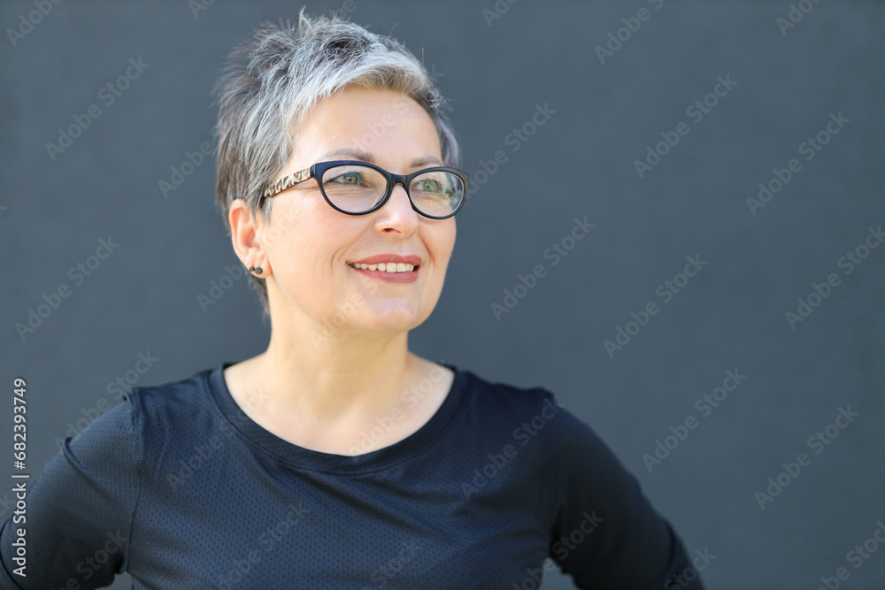 Portrait of a confident and happy mature woman in a city setting, exuding elegance and embodying a successful lifestyle. - obrazy, fototapety, plakaty 