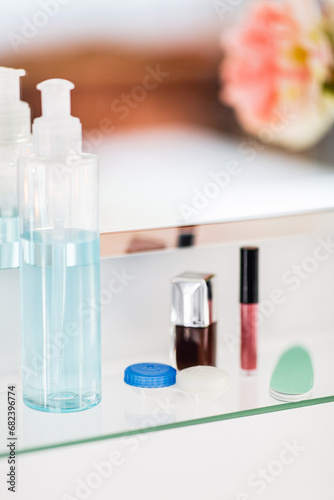 hygiene, beauty and daily routine concept - close up of lotion, nail polish, file and lipstick on mirror shelf in bathroom