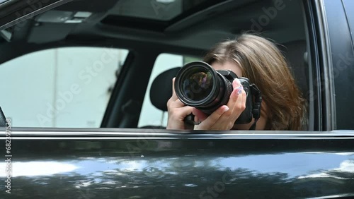 Young woman funny spying and taking photo of someone from car window. Close up