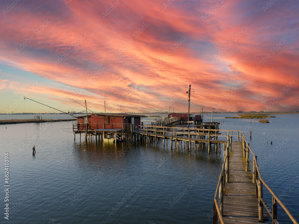 sunset at the pier in the Fishing hut with fishing net in the Comacchio lagoon sunset at the pier in the Fishing hut with fishing net in the Comacchio lagoon