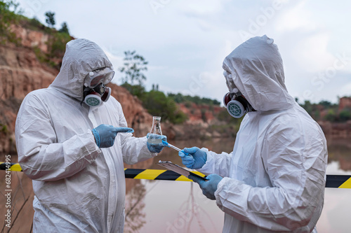 Scientists or biologists wearing protective uniforms working together on water analysis,Environmental engineers inspect water quality in a dangerous area