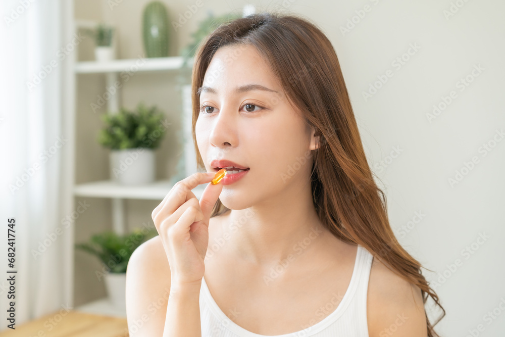 Dietary supplement, pretty asian young woman, girl hand holding medical pill capsule, take or eat vitamin fish oil for treatment for skin, hair and nail strengthener near window at home, healthcare. Dietary supplement, pretty asian young woman, girl hand holding medical pill capsule, take or eat vitamin fish oil for treatment for skin, hair and nail strengthener near window at home, healthcare.