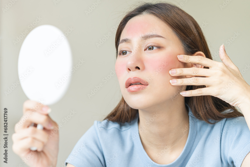 Dermatology, scratch asian young woman looking at mirror, expression worry and itch, itchy allergy or allergic sensitive reaction, red spot or rash on her face. Beauty care from skin problem treatment Dermatology, scratch asian young woman looking at mirror, expression worry and itch, itchy allergy or allergic sensitive reaction, red spot or rash on her face. Beauty care from skin problem treatment