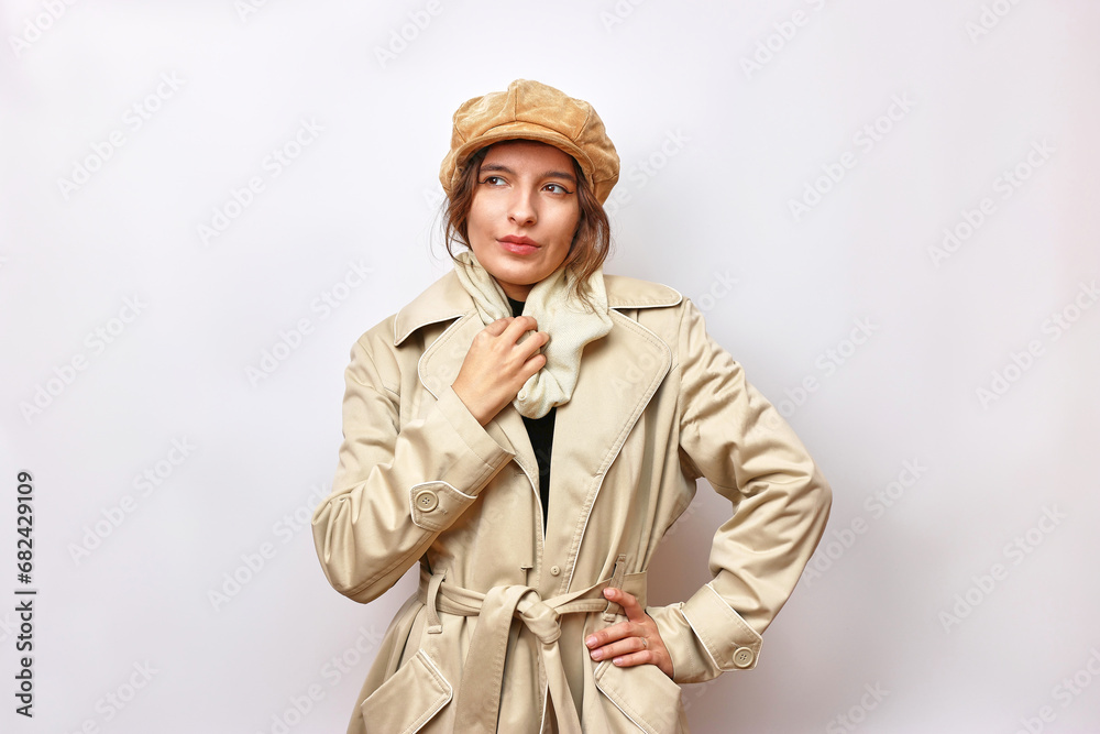 Fototapeta premium A beautiful girl is dressed in a beige autumn raincoat and a brown warm hat.