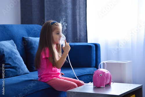 Little girl with inhaler on sofa photo