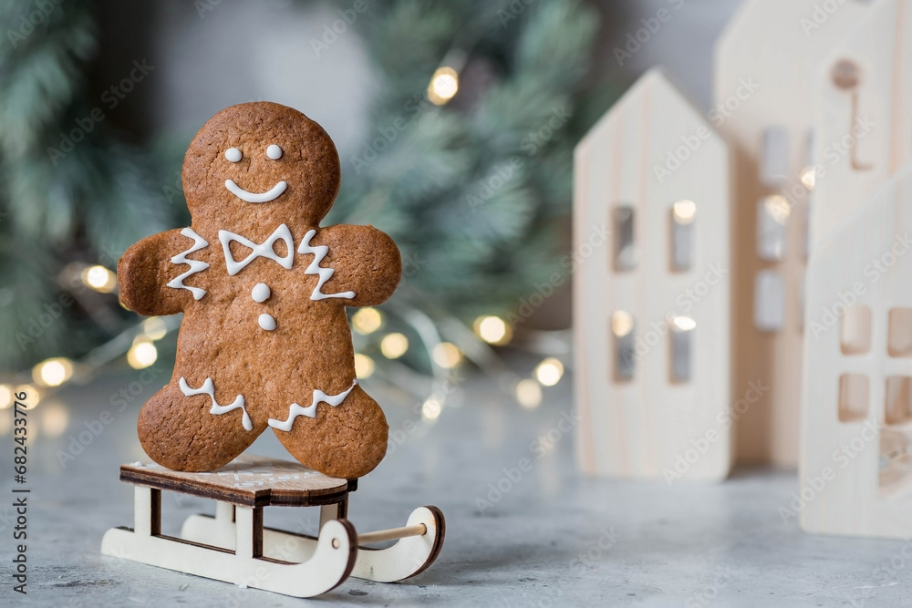 Homemade gingerbread Christmas cookies in icing sugar. Delicious gingerbread cookies on the background of a bokeh of Christmas tree lights. Freshly baked Christmas gingerbread cookies. - obrazy, fototapety, plakaty 