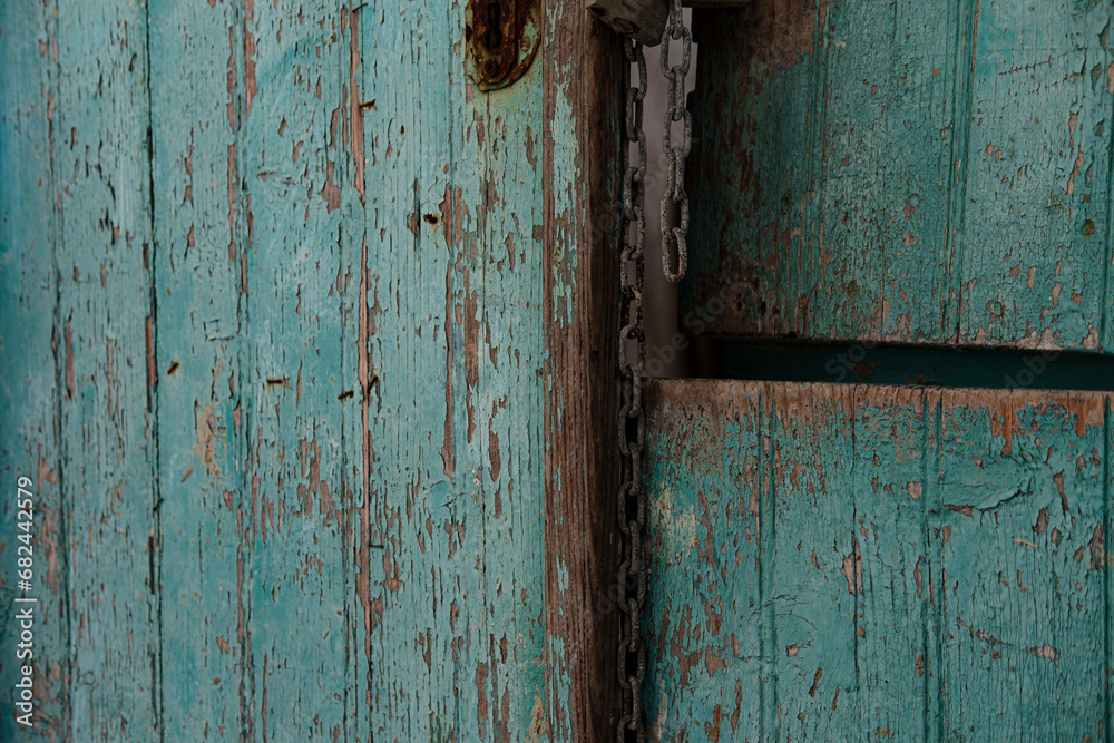 very old turquoise door, rustic paint, broken entrance, rusty metal chain and lock very old turquoise door, rustic paint, broken entrance, rusty metal chain and lock
