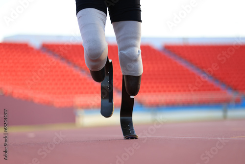 disabled man with a leg prosthesis in sports clothing is running in the stadium © naraichal