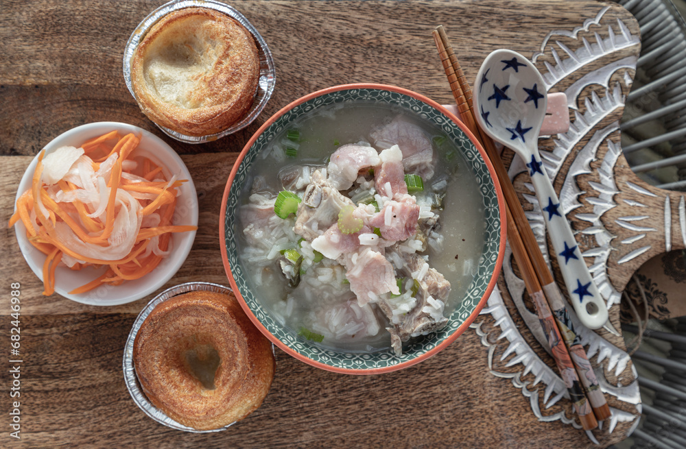 Hot Boiled rice or Rice porridge with Pork spare ribs soup and Ham served with Deep fried dough, Pickled carrot and Radish on Wooden cutting board. Healthy breakfast food, Top view, Copy space, 
