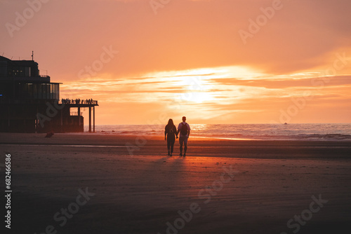 Romantic walk of a young couple on the beaches of Oostende in western Belgium at sunset. Love and devotion. Reflection in a pool of water
